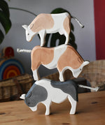 Ostheimer black and white ox, brown and white ox and a brown and white cow wooden toy figures stacked on top of each other.