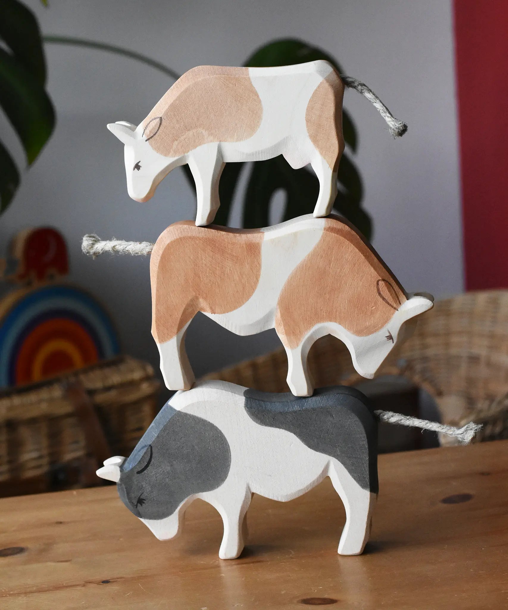 Ostheimer black and white ox, brown and white ox and a brown and white cow wooden toy figures stacked on top of each other.