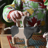 Child placing an Ostheimer brown calf figure on the back of a black and white cow figure.