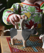 Child placing an Ostheimer brown calf figure on the back of a black and white cow figure.