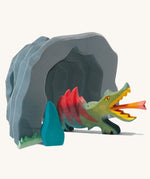 An Ostheimer dragon in an Ostheimer black wooden dragon's cave on a plain background. There are also Ostheimer grass and bushes at the front of the cave.  