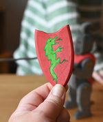 Red Ostheimer black knight shield with green dragon in an adult's hand. 