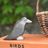 A raven bird figure placed on a pile of old books. 