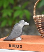 A raven bird figure placed on a pile of old books. 