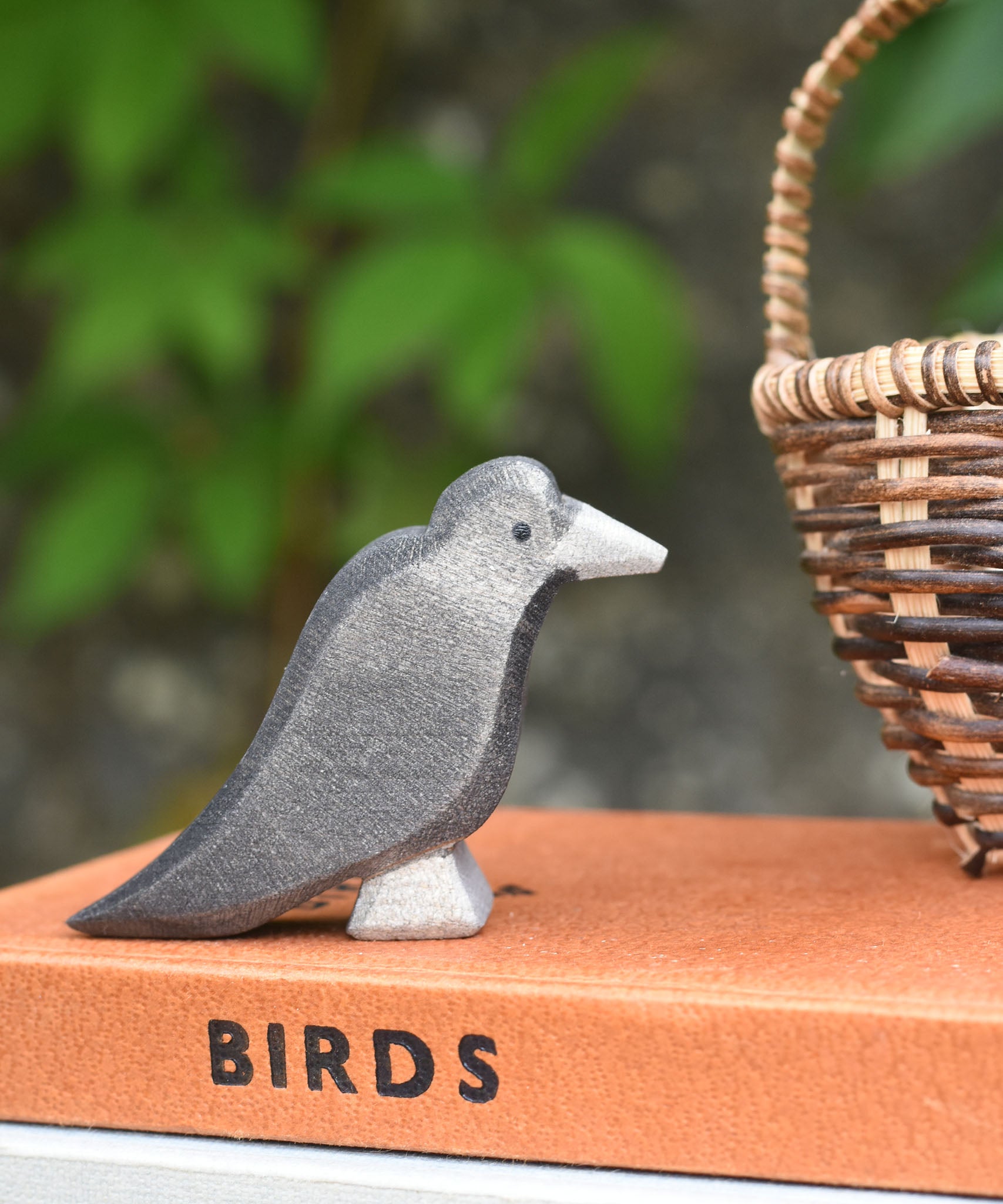 A raven bird figure placed on a pile of old books. 