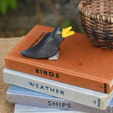 An Ostheimer blackbird wooden figure placed on a pile of old books. 