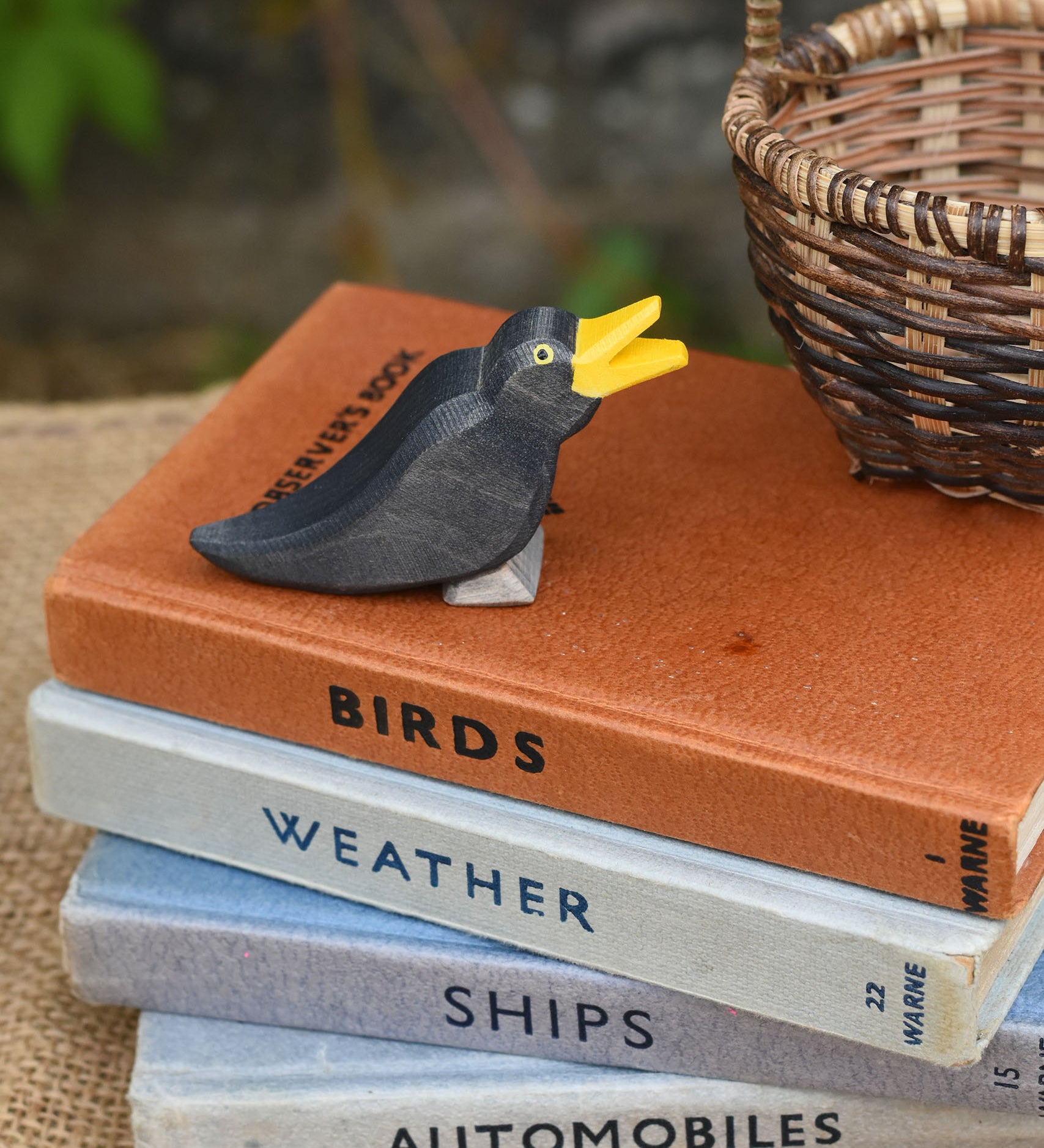 An Ostheimer blackbird wooden figure placed on a pile of old books. 