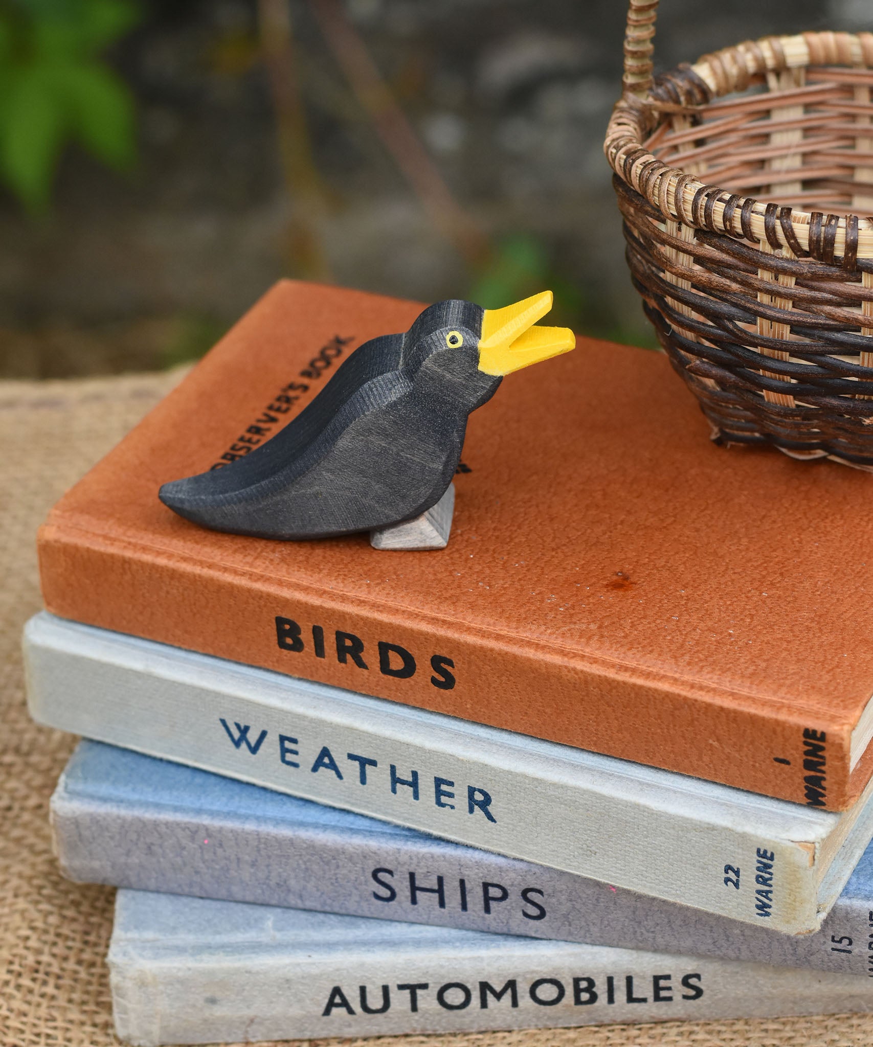 An Ostheimer blackbird wooden figure placed on a pile of old books. 