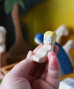 Baby Jesus from the Ostheimer wooden toy nativity set in an adult's hand.
