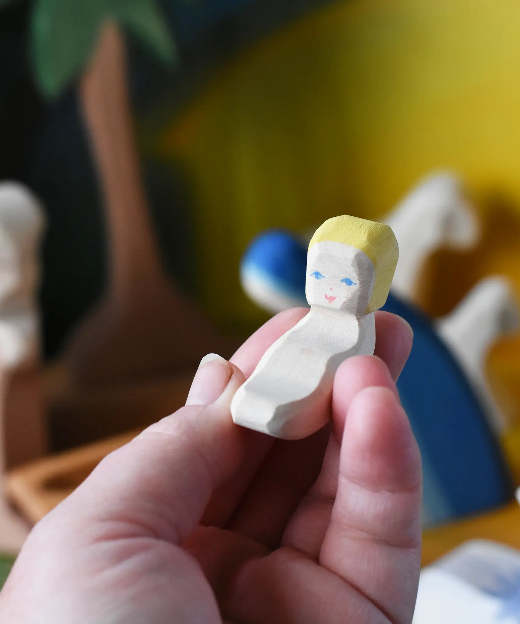 Baby Jesus from the Ostheimer wooden toy nativity set in an adult's hand.