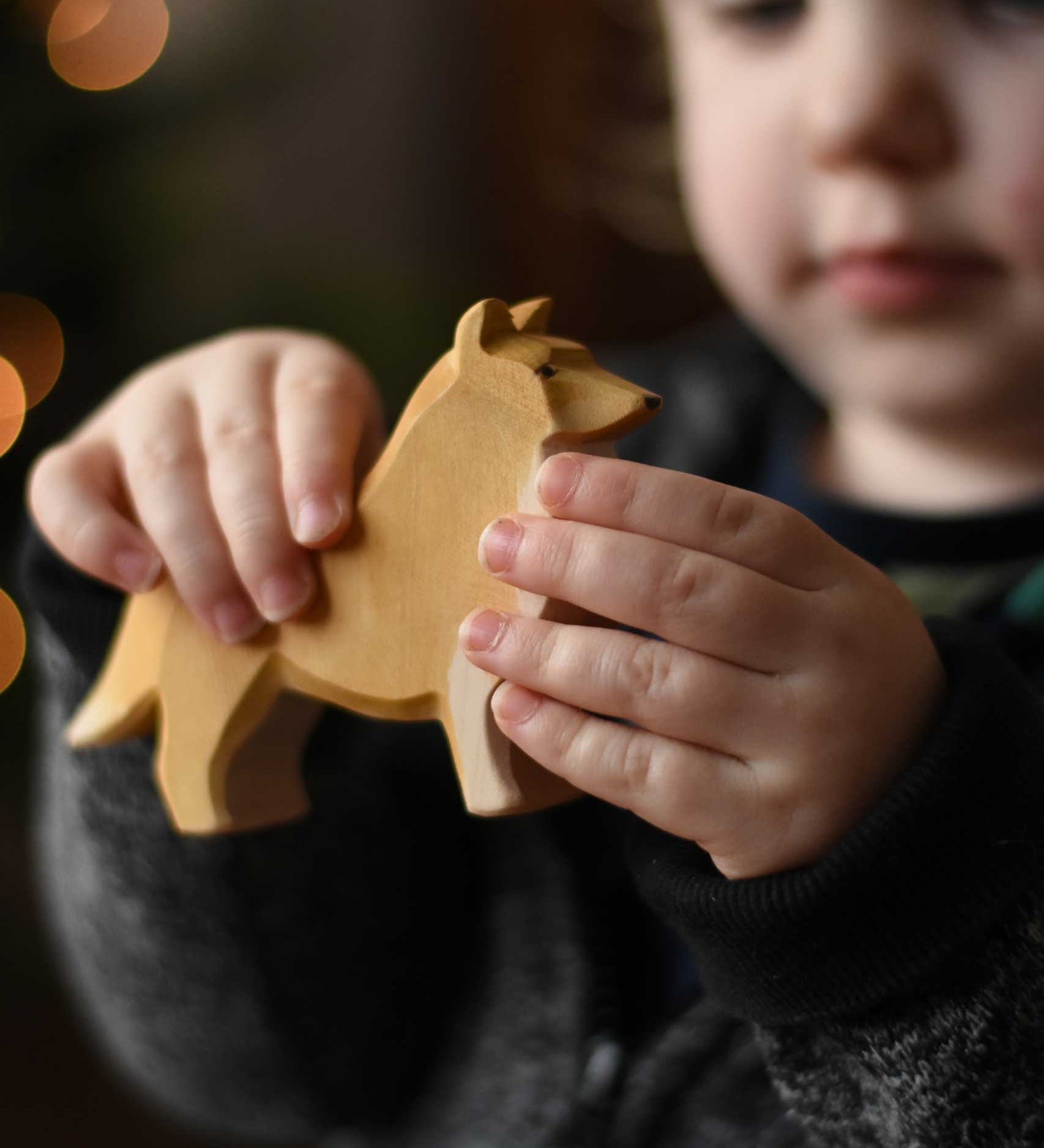 A close up of the Ostheimer collie dog wooden toy figure in a child's hand.  These wooden figures are part of a wide range of expertly hand crafted wooden toys here at Babipur. 