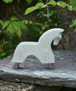 The Ostheimer blue horse toy figure placed on a slate surface outdoors.