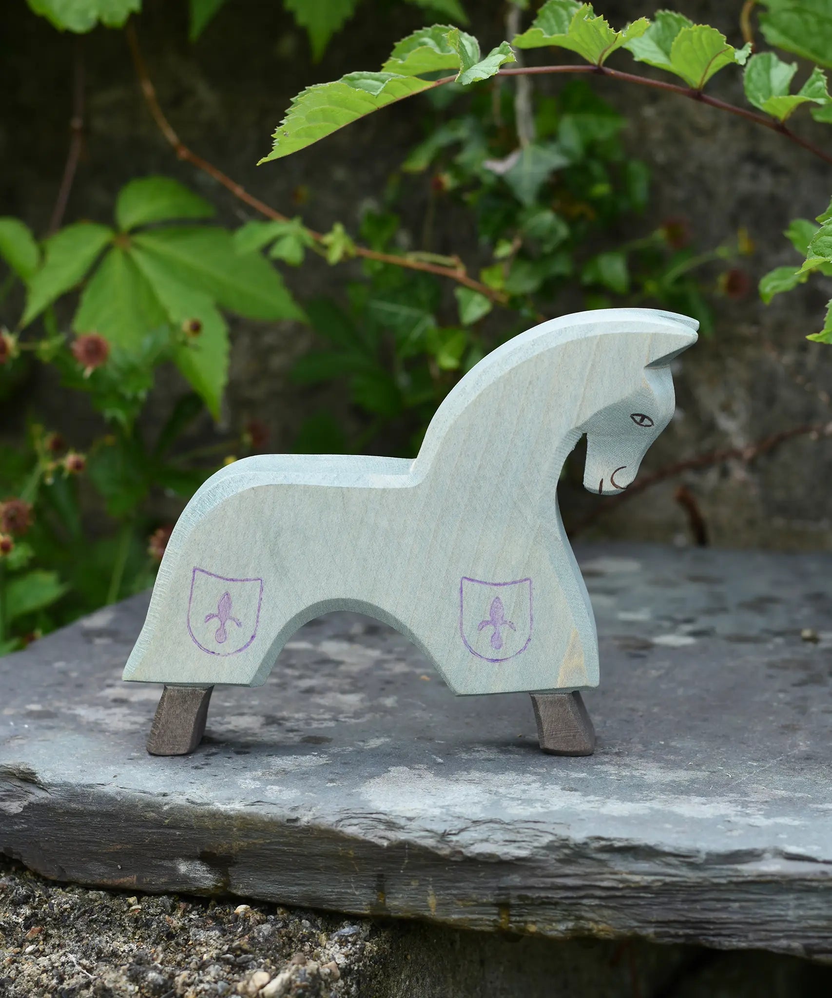 The Ostheimer blue horse toy figure placed on a slate surface outdoors.