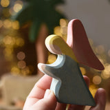 Ostheimer blue kneeling angel wooden toy figure in an adult's hand.