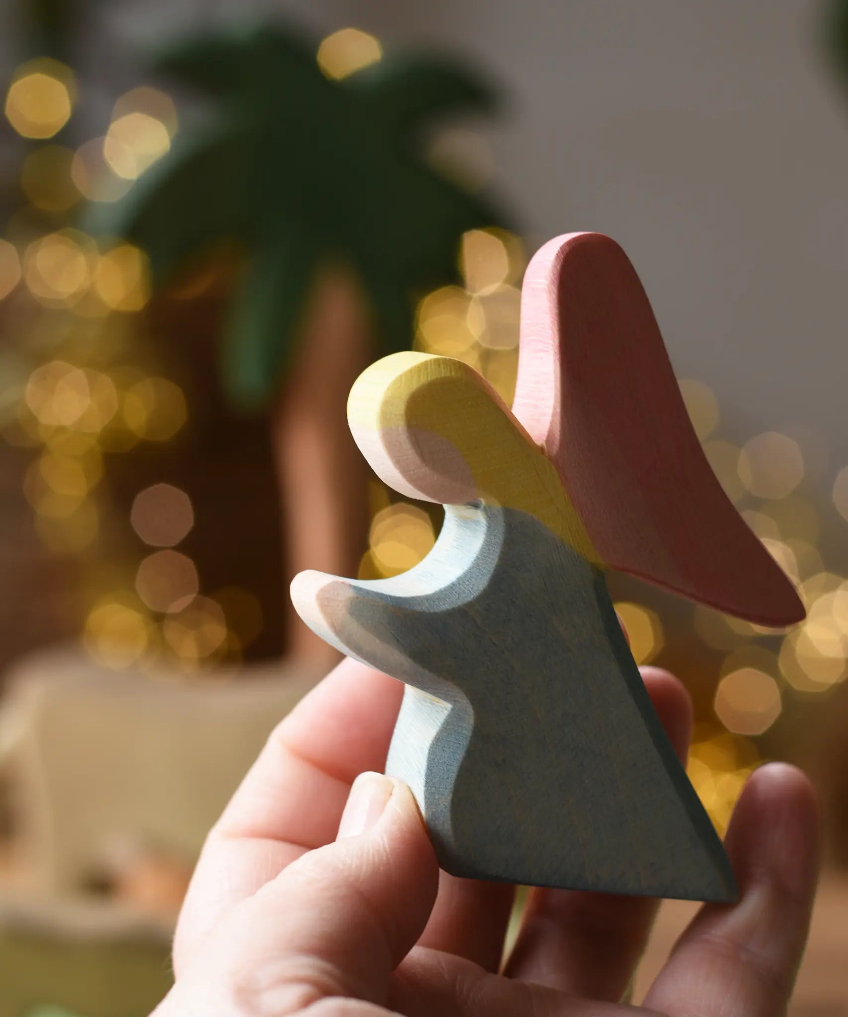 Ostheimer blue kneeling angel wooden toy figure in an adult's hand.