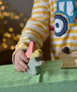 Ostheimer blue kneeling angel wooden toy figure in a child's hand being placed on a green cotton play cloth in a small world play scene.
