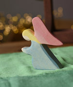 Ostheimer blue kneeling angel wooden toy figure placed on a green cotton play cloth.