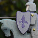 Close up of the shield on the Ostheimer blue riding wooden knight on a grey horse toy figure.