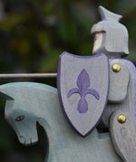 Close up of the shield on the Ostheimer blue riding wooden knight on a grey horse toy figure.