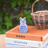 A Ostheimer blue owl wooden toy figure placed on a pile of books. 