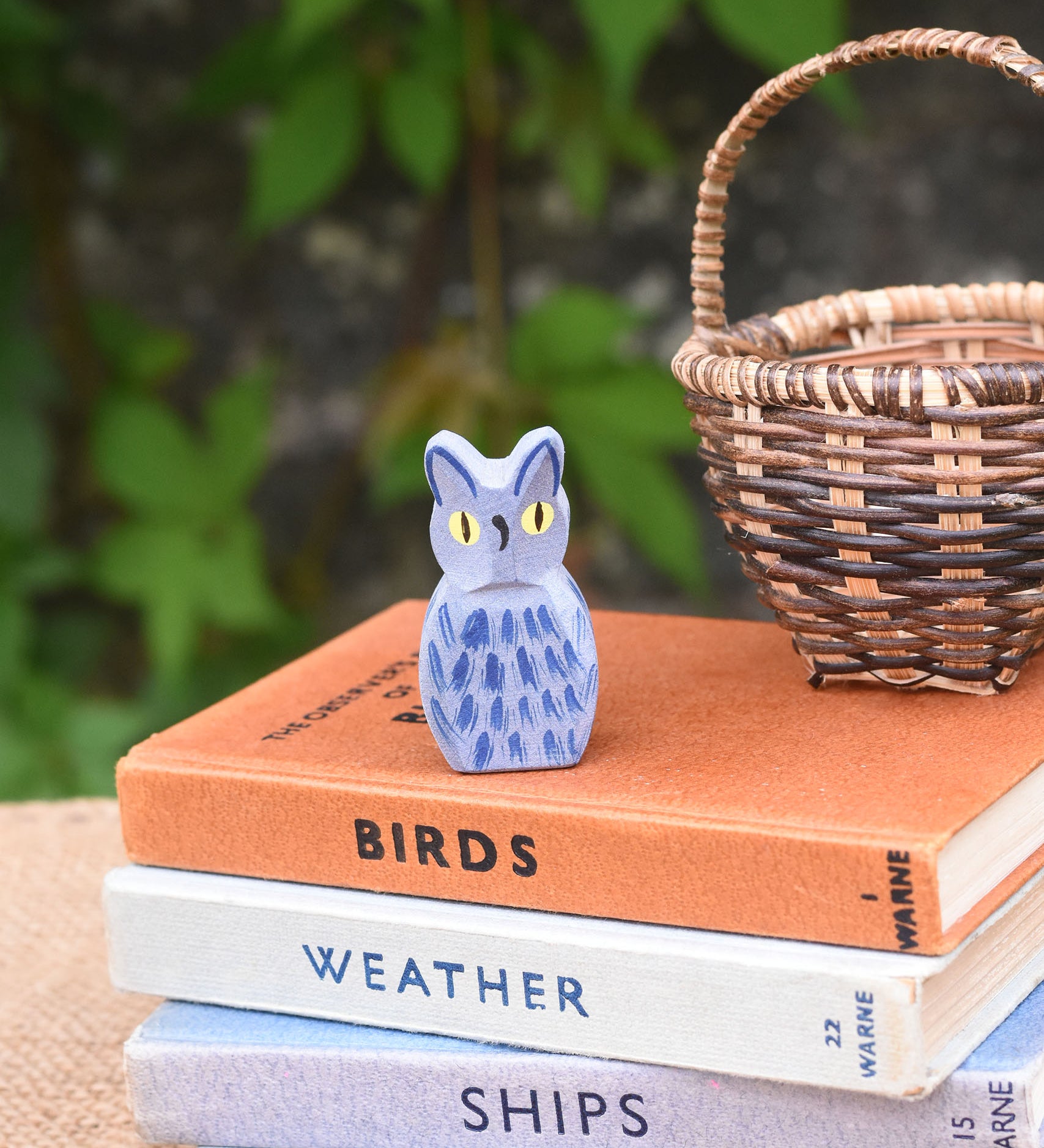 A Ostheimer blue owl wooden toy figure placed on a pile of books. 