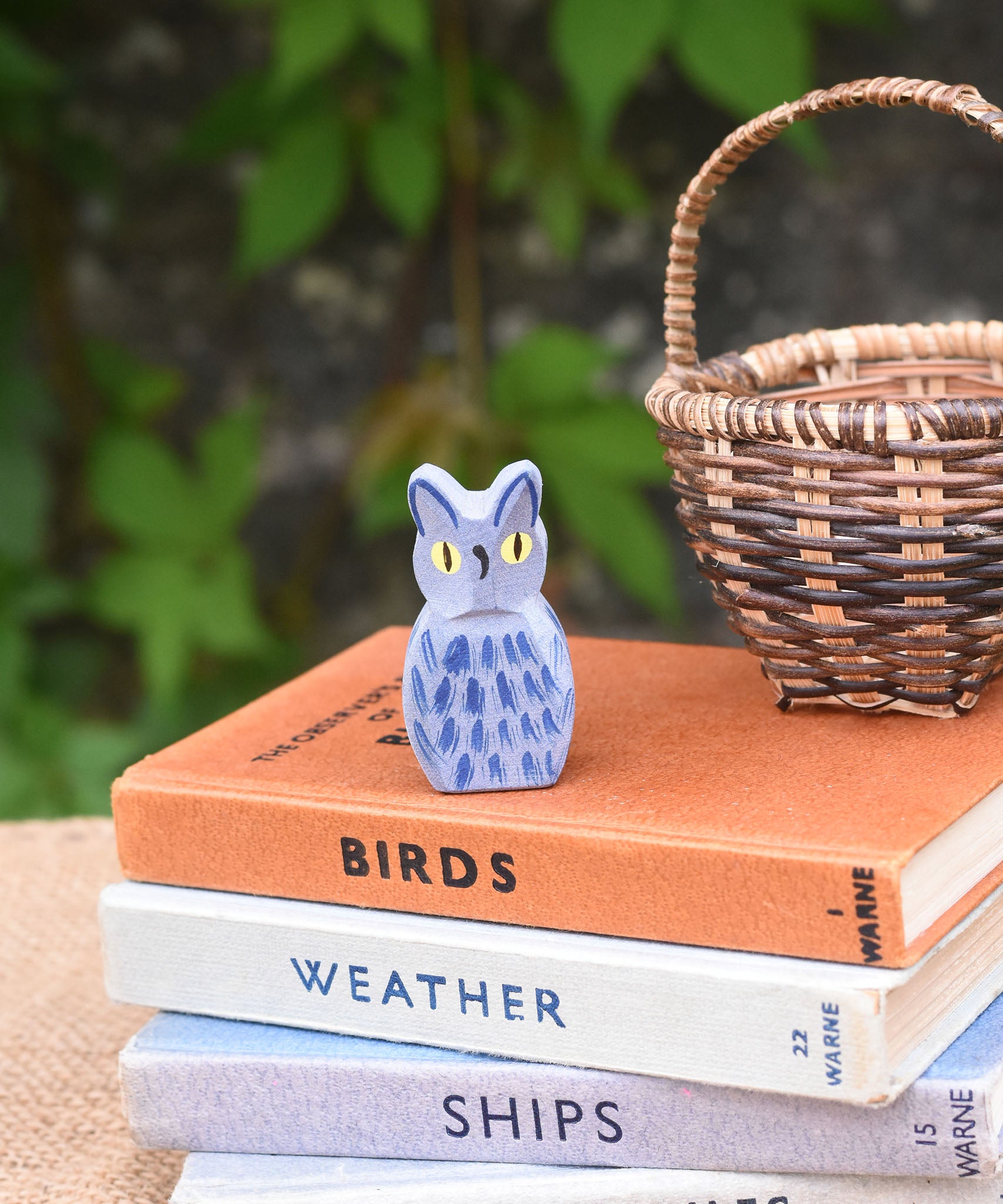 A Ostheimer blue owl wooden toy figure placed on a pile of books. 