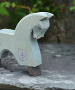 The Ostheimer blue horse toy figure placed on a slate surface outdoors.