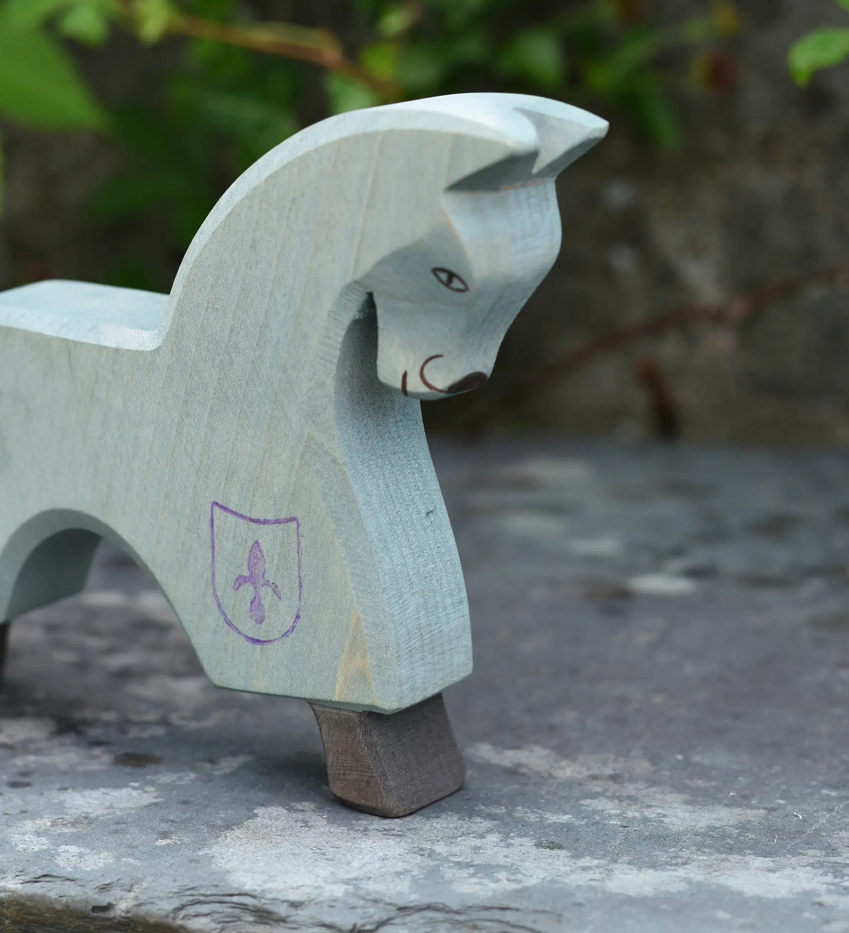 The Ostheimer blue horse toy figure placed on a slate surface outdoors.