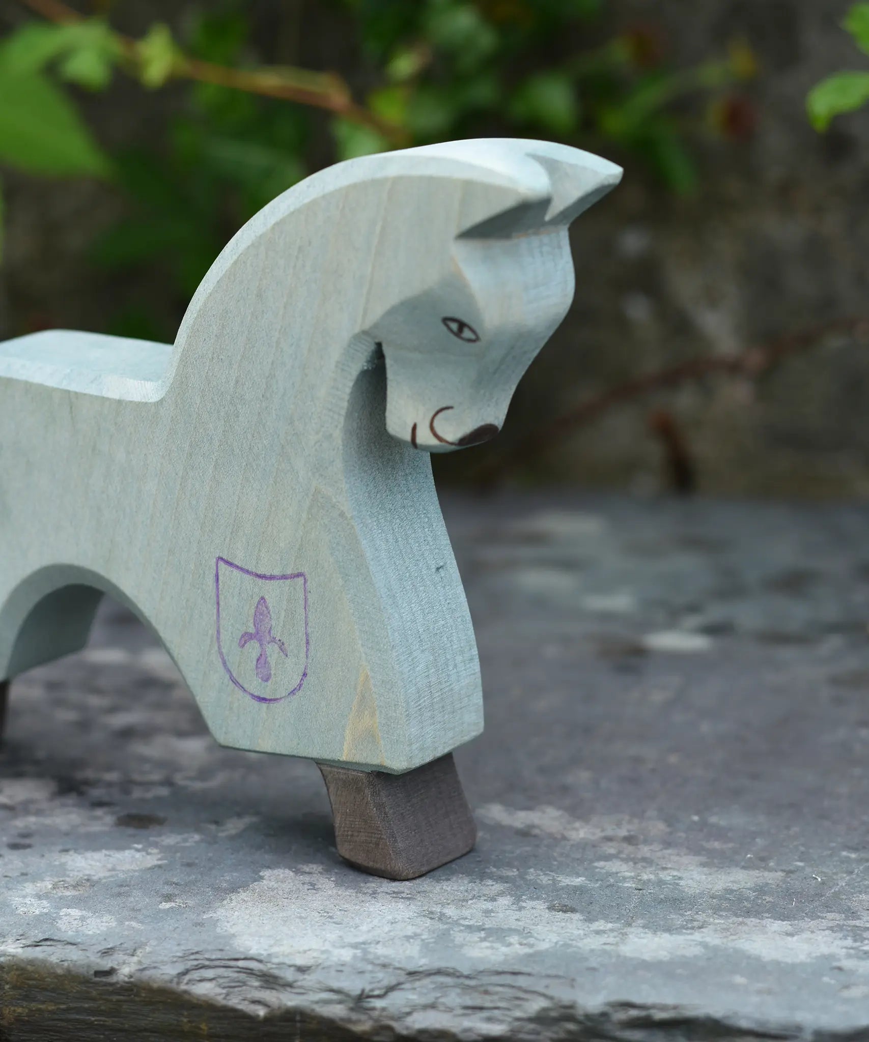 The Ostheimer blue horse toy figure placed on a slate surface outdoors.