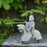 The Ostheimer blue riding wooden knight on a grey horse toy figure placed on a slate surface outdoors.