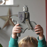 The Ostheimer blue riding wooden knight on a grey horse toy figure held up by a child. 