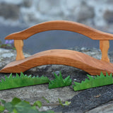 An Ostheimer wooden bridge with railing placed on a stone wall outdoor. Ostheimer grass pieces have been placed in front of the bridge.