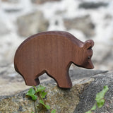 Ostheimer brown bear wooden toy figure placed on a stone wall outdoors.