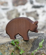 Ostheimer brown bear wooden toy figure placed on a stone wall outdoors.