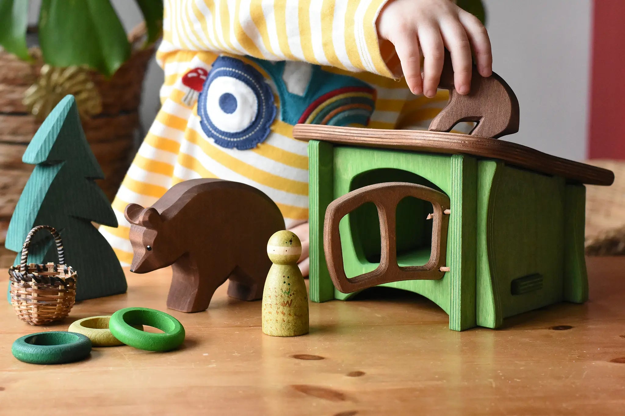 Small world play scene with Ostheimer brown bears  wooden toy figures small spruce tree and green hutch and Grapat peg dolls and rings. 