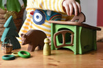 Small world play scene with Ostheimer brown bears  wooden toy figures small spruce tree and green hutch and Grapat peg dolls and rings. 