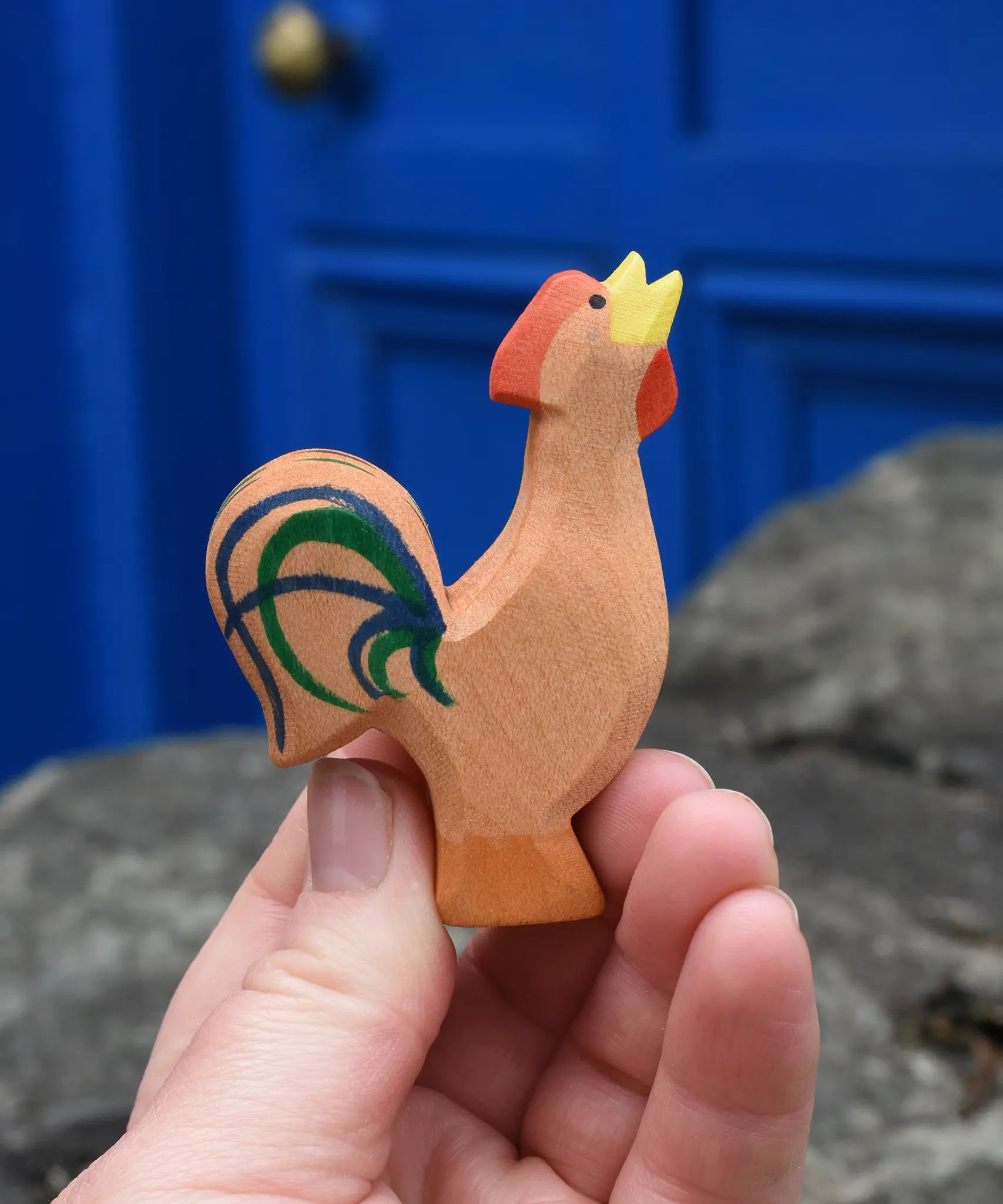 Ostheimer brown bremer rooster wooden toy figure in an adult's hand.
