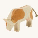 Ostheimer Brown Cow Eating wooden toy figure on a plain background. 