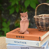 An Ostheimer brown coloured eagle owl placed on a pile of books next to a Kraul basket. The owl figure is part of a large collection of expertly hand crafted wooden toys and figures here at Babipur. 