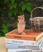 An Ostheimer brown coloured eagle owl placed on a pile of books next to a Kraul basket. The owl figure is part of a large collection of expertly hand crafted wooden toys and figures here at Babipur. 