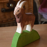 Ostheimer brown male goat wooden toy figure on a green wooden bush piece. 