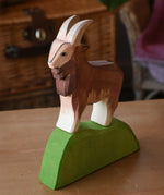 Ostheimer brown male goat wooden toy figure on a green wooden bush piece. 