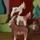 Three wooden toy goat figures stacked up on top of each other the Ostheimer brown male goat is at the bottom. 