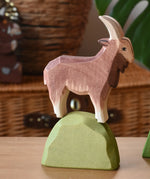 Ostheimer brown male goat wooden toy figure on a green bush piece. 