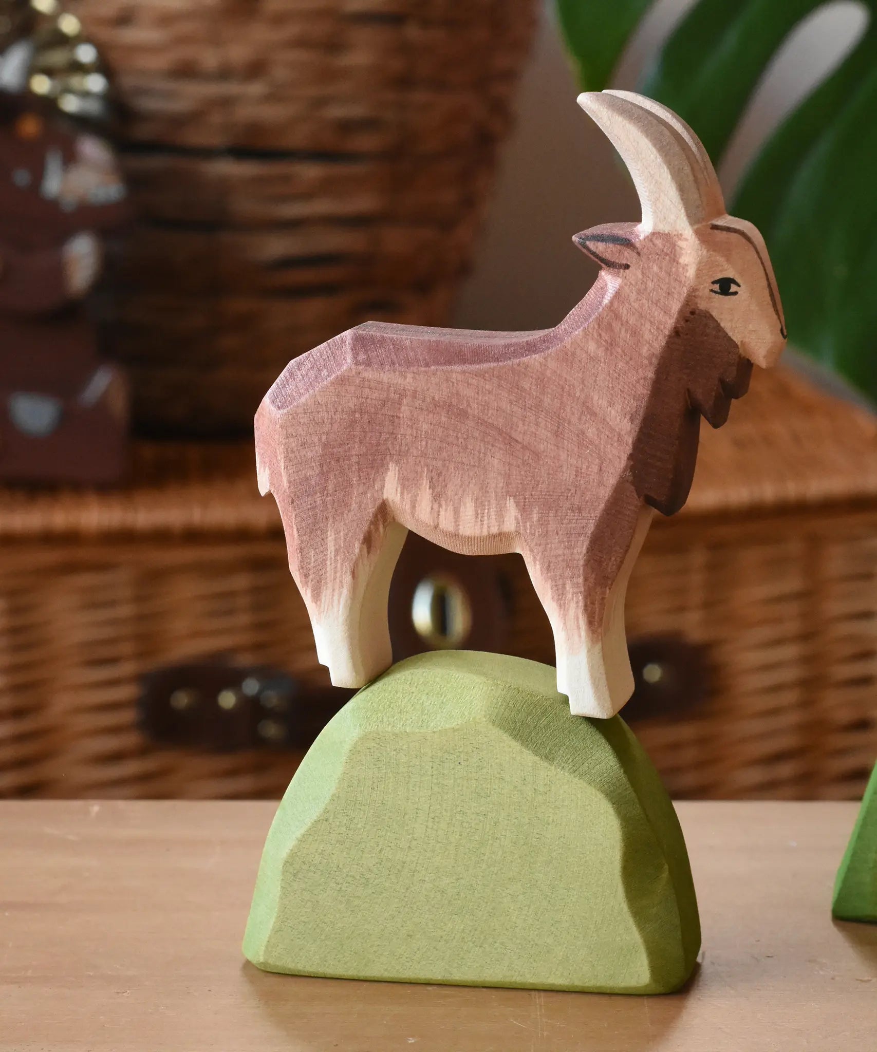 Ostheimer brown male goat wooden toy figure on a green bush piece. 
