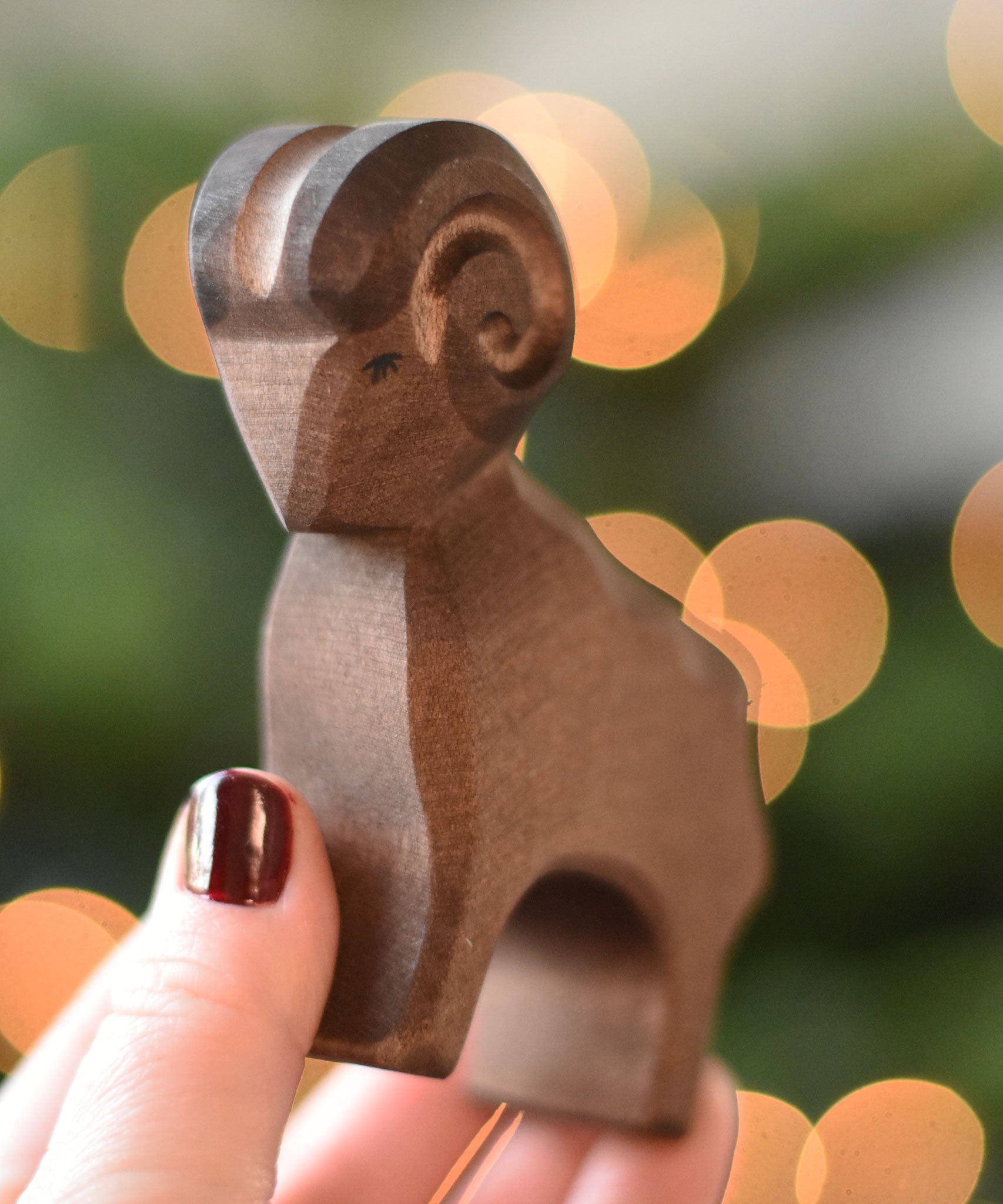 An Ostheimer Brown ram wooden toy figure in an adult's hand. This wooden figure is part of a large range of expertly hand crafted, Waldorf inspired, wooden toys here at Babipur. 