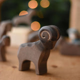 An Ostheimer Brown ram wooden toy figure placed on a wooden toy surface. This wooden figure is part of a large range of expertly hand crafted, Waldorf inspired, wooden toys here at Babipur. 
