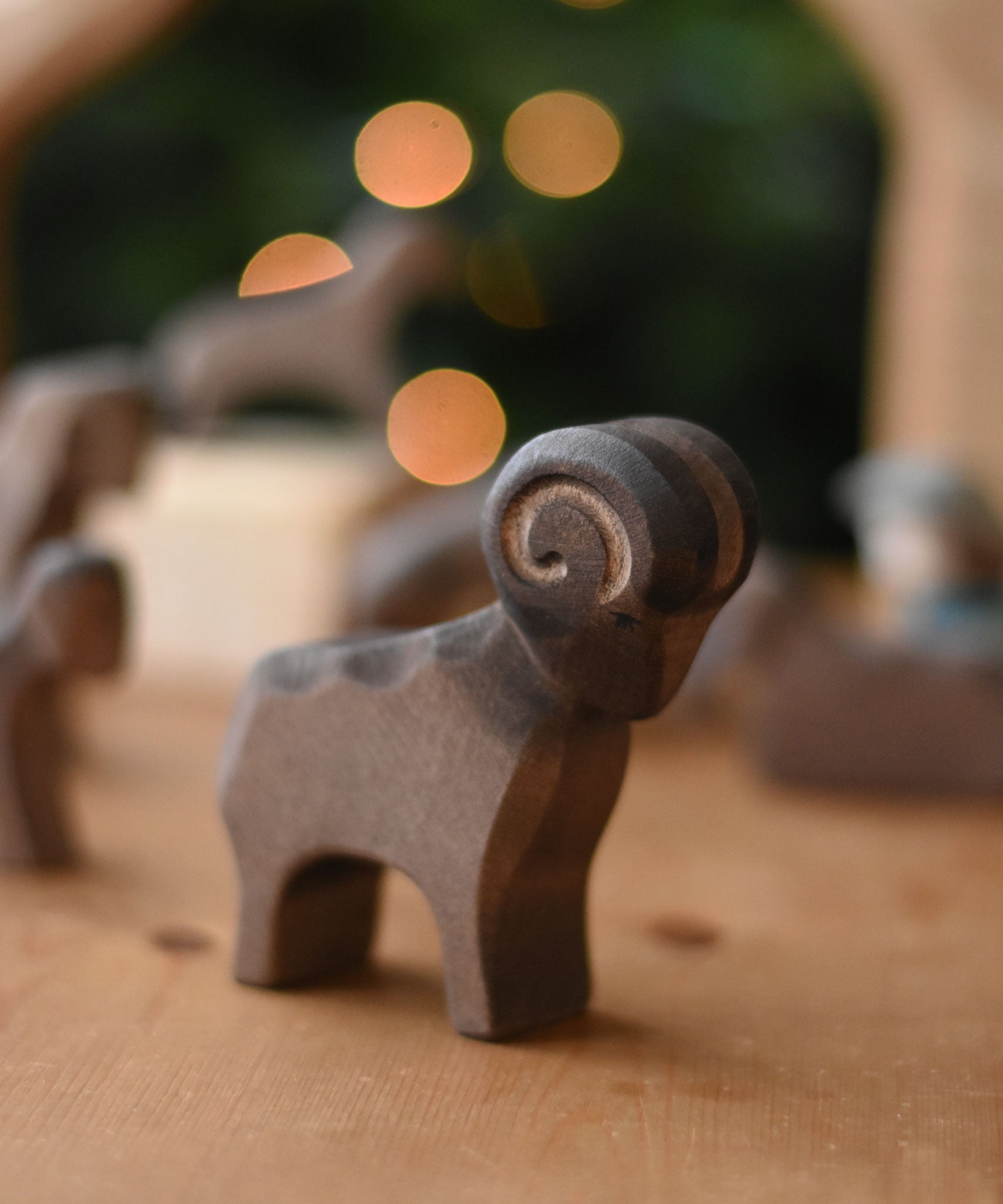 An Ostheimer Brown ram wooden toy figure placed on a wooden toy surface. This wooden figure is part of a large range of expertly hand crafted, Waldorf inspired, wooden toys here at Babipur. 