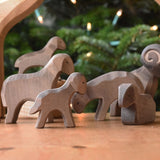 A collection of Ostheimer Brown Sheep wooden toy figures placed on a wooden surface along with a shepherd and shepherd's dog. These wooden figure is part of a large range of expertly hand crafted, Waldorf inspired, wooden toys here at Babipur. 