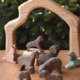 A collection of Ostheimer Brown Sheep wooden toy figures placed on a wooden surface along with a shepherd and shepherd's dog. These wooden figure is part of a large range of expertly hand crafted, Waldorf inspired, wooden toys here at Babipur. 